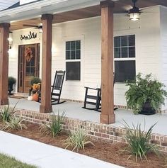 a porch with two rocking chairs on it and plants in the foreground, along with an awning for shade