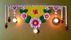 a decorative wall hanging with flowers and candles on it's side in front of a yellow background