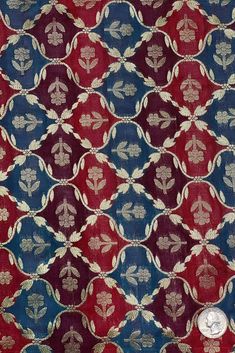 a red, blue and white fabric with gold leaf design on the bottom half of it