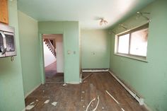 an empty room with green walls and wood flooring in the process of being painted