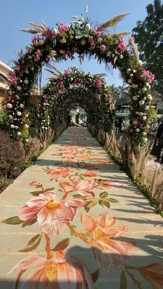 an outdoor walkway decorated with flowers and greenery