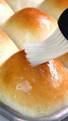 bread rolls being spread with an onion slice on top in a baking pan, ready to be baked