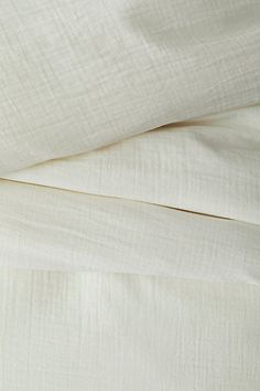 an unmade bed with white sheets and pillows