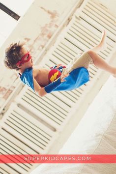 a young boy dressed as superman is jumping in the air