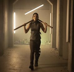 a woman holding two large wooden sticks in her hands while walking through an empty room