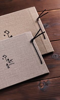 two linen notebooks with black writing on them