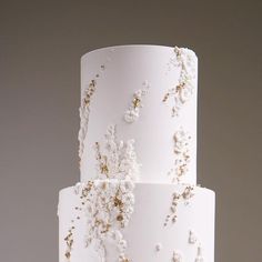 a three tiered white cake with gold decorations