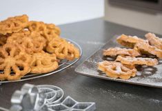 two trays filled with powdered sugar covered pretzels on top of a table