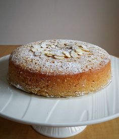 a cake on a plate with powdered sugar and almonds around the edges, ready to be eaten