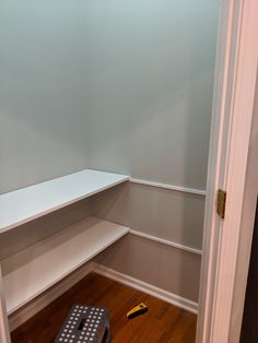 an empty room with white shelves and wooden flooring next to a blue box on the ground