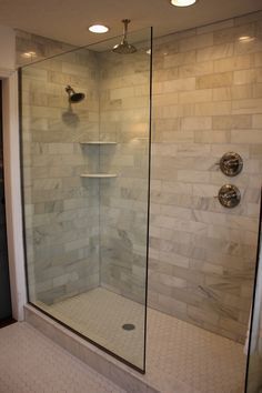 a walk in shower sitting next to a white tiled wall and floor with two lights on each side