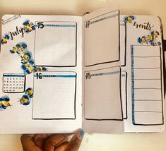 a hand holding a notebook with the pages lined in blue and yellow flowers on it