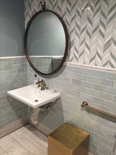 a white sink sitting under a round mirror in a bathroom next to a gold stool