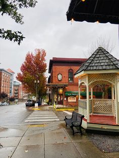 a small wooden gazebo sitting on the side of a road next to a street