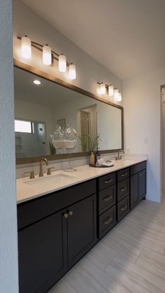 a bathroom with double sinks and large mirror above it's counter top, along with two lights on either side of the sink