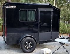 a small black trailer parked next to a picnic table