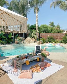 a patio with a table, couch and pool in the backround near palm trees