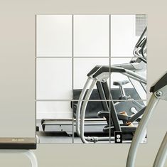 an exercise room with treadmills and mirrors on the wall in front of it