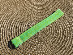 a green and white polka dot tie laying on top of a brown mat with circles