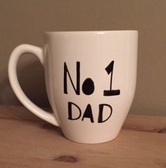 a white coffee mug with the words no 1 dad written on it, sitting on a wooden table