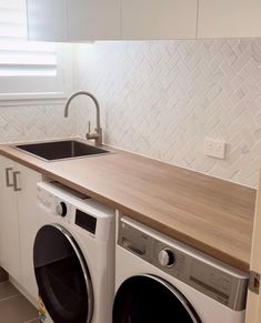 a washer and dryer in a kitchen with white tile backsplashing