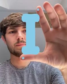 a man holding up a blue letter in front of his face with the letter i on it