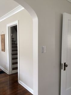 an empty room with white walls and wood floors is seen from the doorway to the hallway