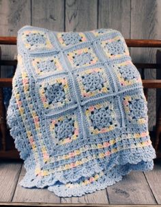 a crocheted blanket sitting on top of a wooden bench