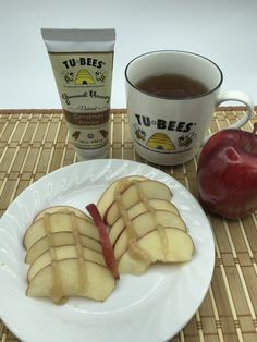 sliced apples on a white plate next to a cup of tea and an apple slice