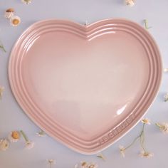 a pink heart shaped plate sitting on top of white flowers