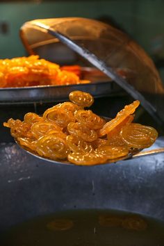 a spoon full of candies sitting on top of a metal pan next to another bowl