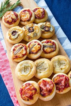 several small pastries are on a wooden platter next to a pink towel and rosemary sprig