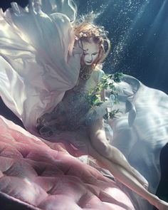 a woman in a white dress floating under water