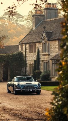 an old car parked in front of a large house on a dirt road next to trees