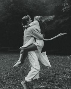 black and white photograph of two people in the grass with their arms around each other