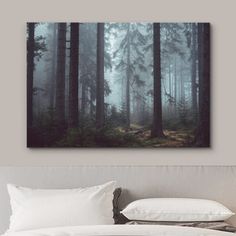 a bed with white pillows and a painting on the wall above it that has a forest scene