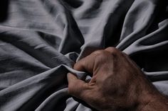 an older man's hand is holding the edge of his bed sheet