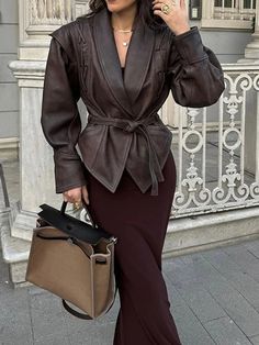 a woman is walking down the street talking on her cell phone and holding a purse