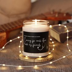 a candle that is sitting on a table next to some string lights and a guitar