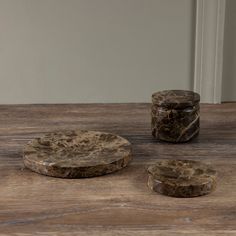 three marble coasters sitting on top of a wooden table next to two jars with lids