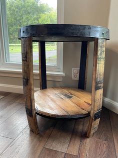 a round wooden table sitting on top of a hard wood floor next to a window