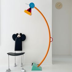 a room with a chair, lamp and mickey mouse head on the wall next to it