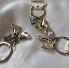 two metal key chains with dinosaur charms attached to them on a white cloth covered surface