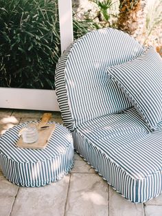 two blue and white striped chairs sitting next to each other on a patio with plants in the background