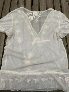 This antique cream blouse is made of a light see through netting fabric with pretty embroidery. It has short sleeves and a dropped waist with ribbon ties for adjustment.  It has no fastenings and is loose enough to put on over the head. The brand is CCDK, and it is marked size 38, which is a UK Size 12. It is in excellent vintage condition. Cream Short Sleeve Blouse For Summer, Bohemian Lace Tops With Short Sleeves, Summer Mesh Top With Lace Trim, Bohemian Lace Short Sleeve Tops, Summer Lace Mesh Top, Elegant Sheer Short Sleeve Mesh Top, Cream Bohemian Short Sleeve Blouse, Cream Bohemian Blouse With Short Sleeves, Bohemian Cream Blouse With Short Sleeves