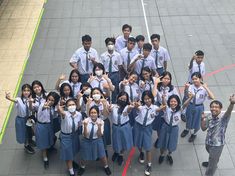 a group of young people standing next to each other on top of a tarmac