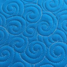 a close up view of a blue quilt with white stitching and circles on it