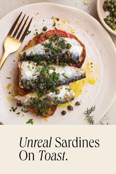 there is a white plate with two fish on it and the words unerall sardines on toast