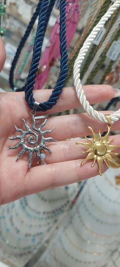 a person holding three different necklaces in their hand, one with a sun and the other with a star