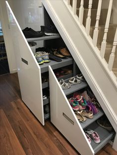 an under the stairs shoe storage unit with shoes in it on top of wooden flooring